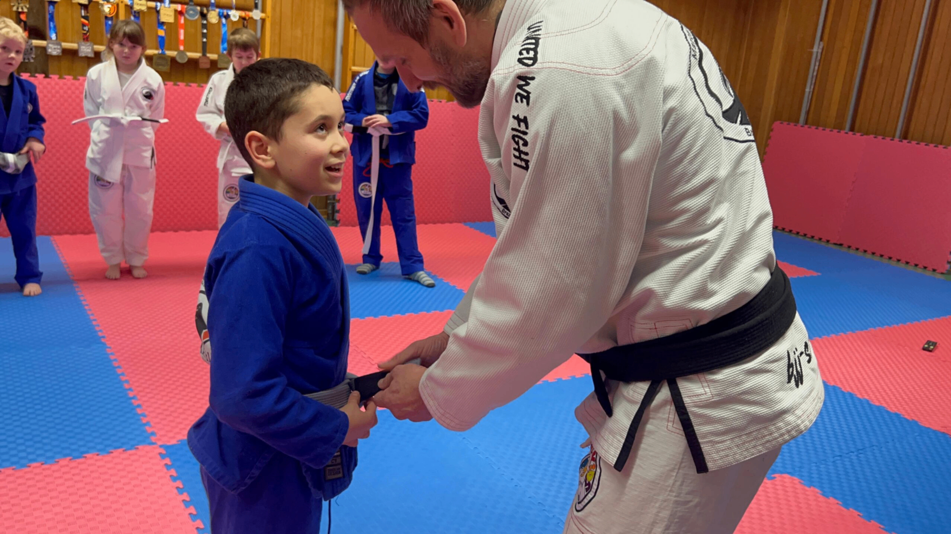Coach bindet einem Kind den Gürtel, Kids Class